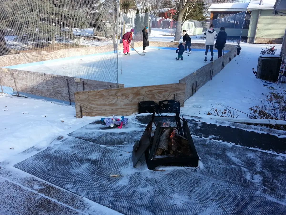 Kids and parents skating on a boarded backyard rink on a winter afternoon