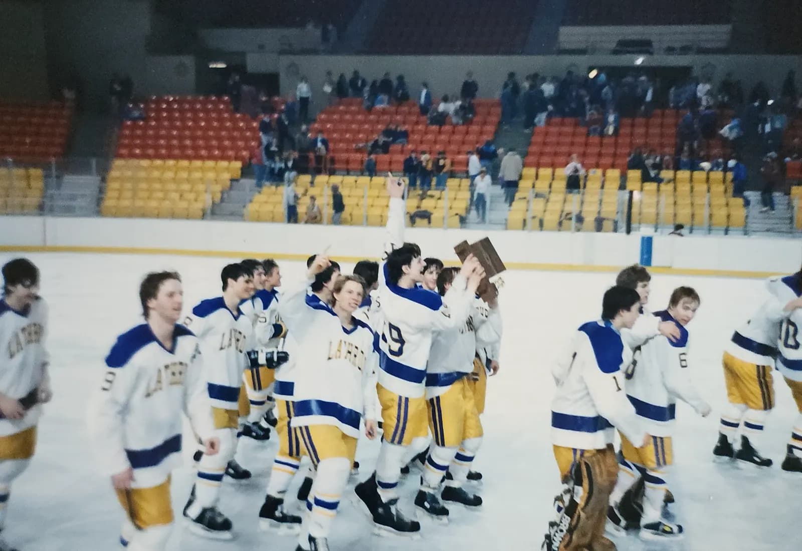 Lathrop players skating off the ice in blue and gold, the state championship plaque held overhead — Fairbanks, 1986