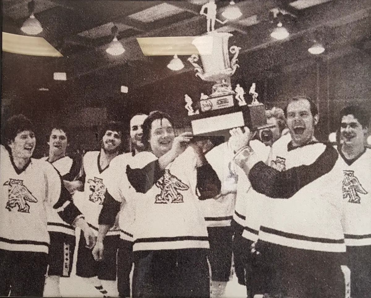 Newspaper photo of the Augsburg team hoisting the national championship trophy in the locker room, early 1980s